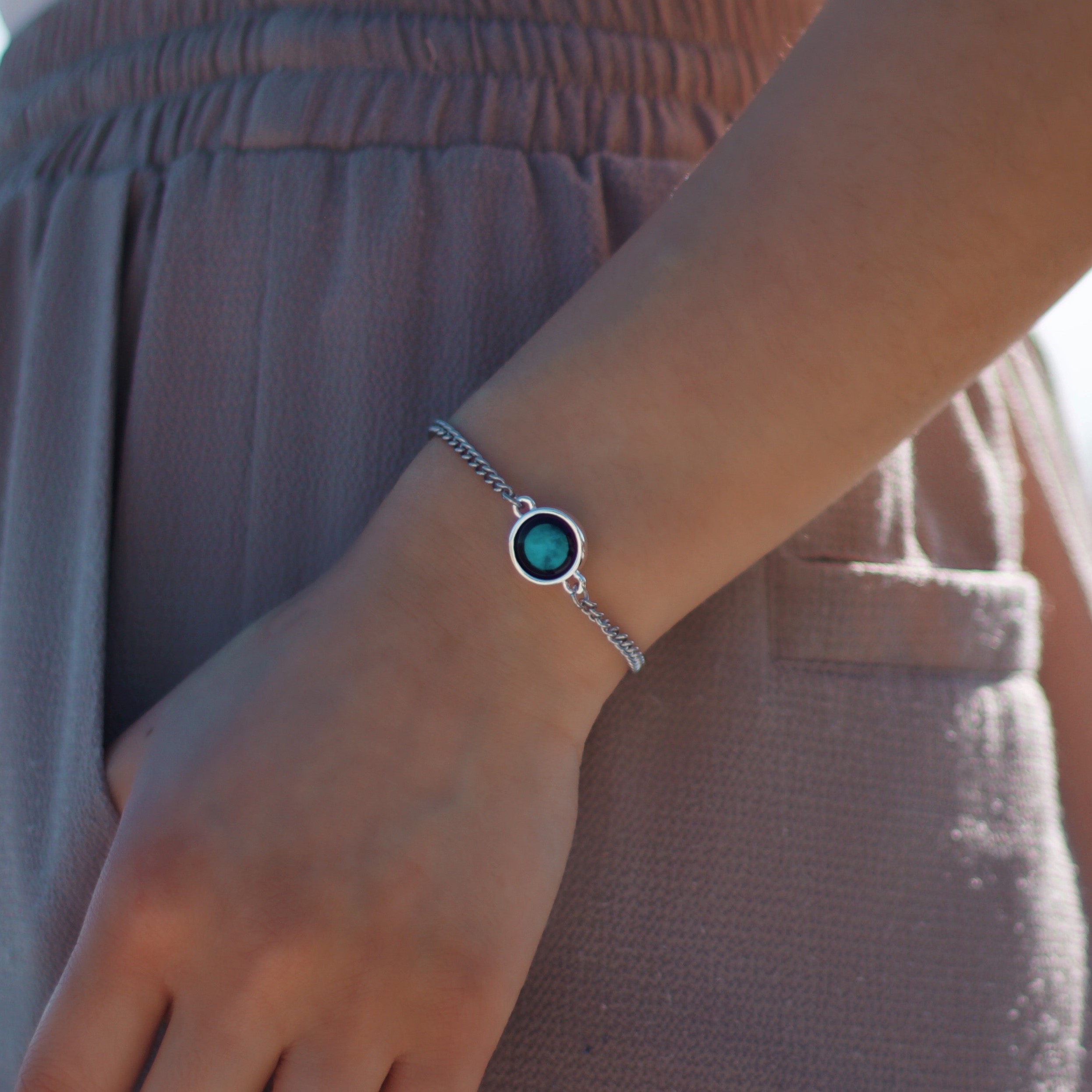 A silver bracelet with a round blue charm