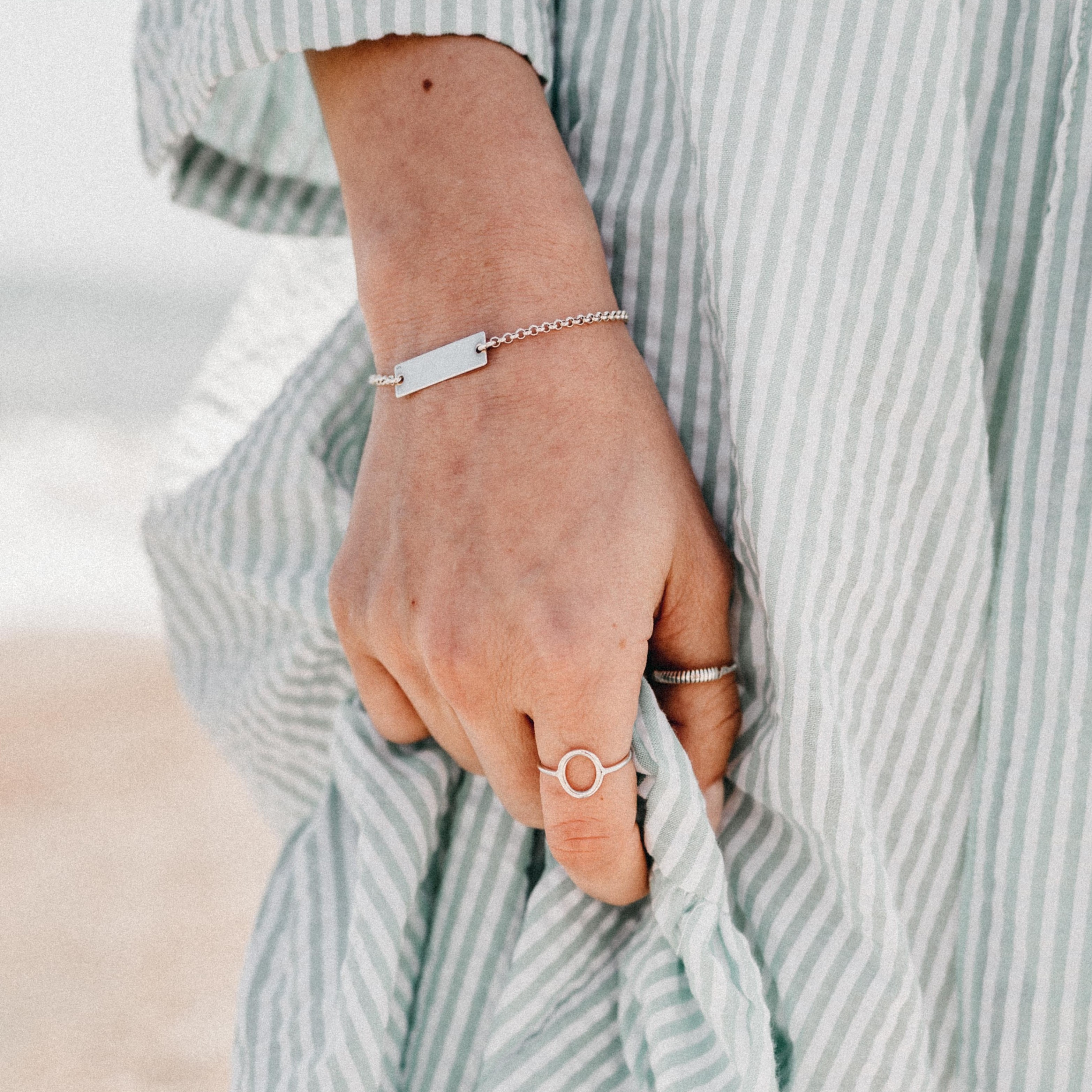 A silver bracelet with a thin chain and one rectangular charm