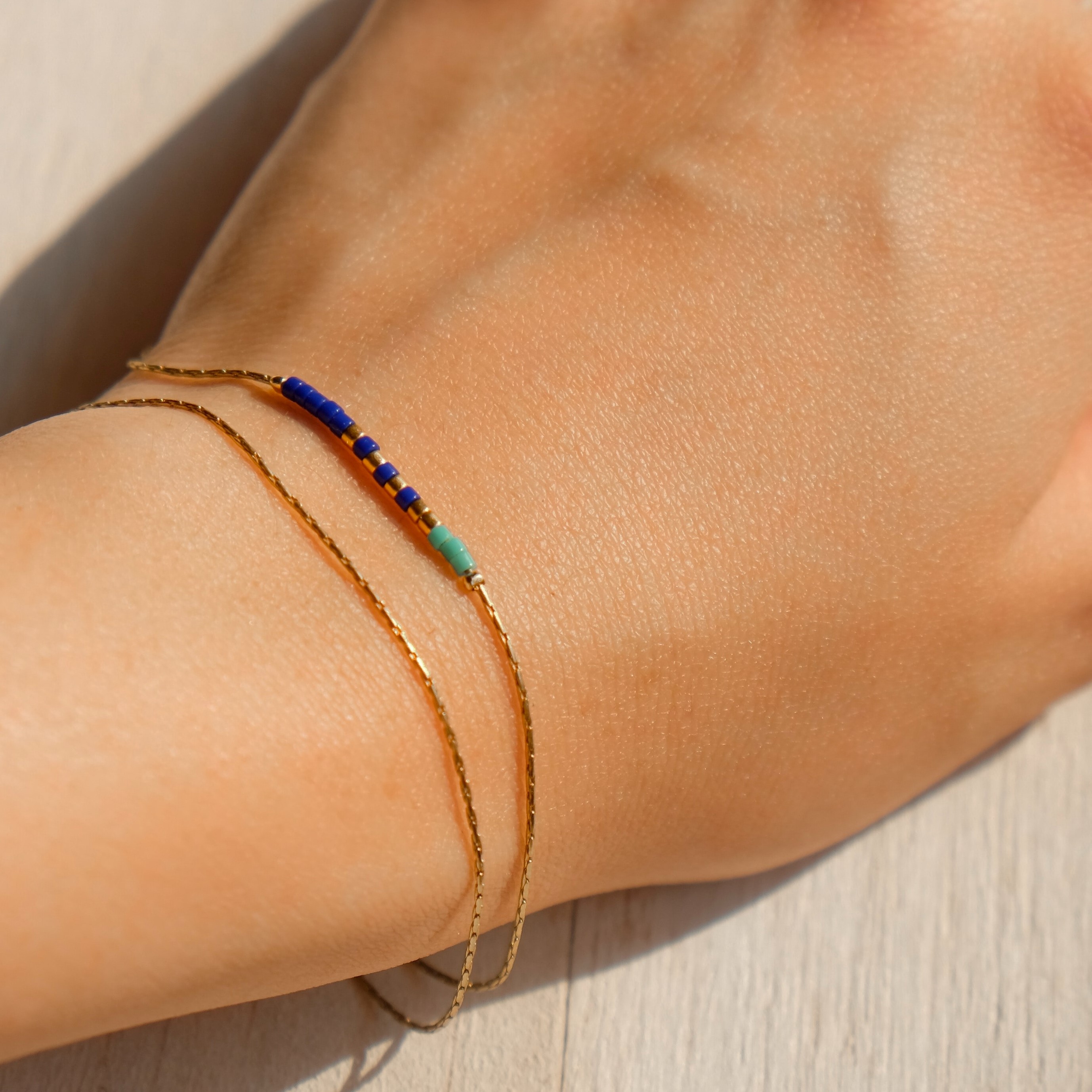 A gold bracelet with a very thin chain and small blue elements