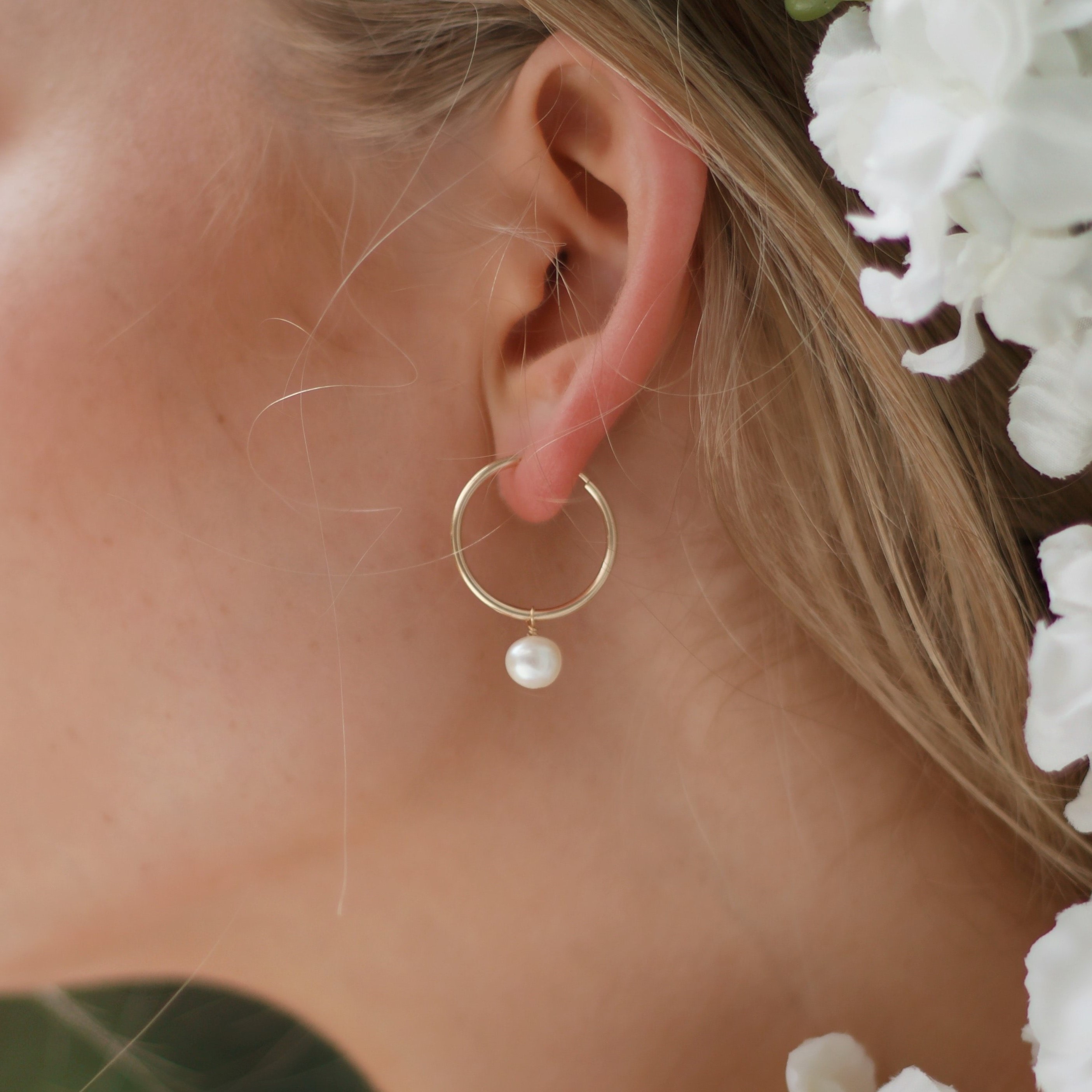 Very thin, round, gold earrings with a pearl