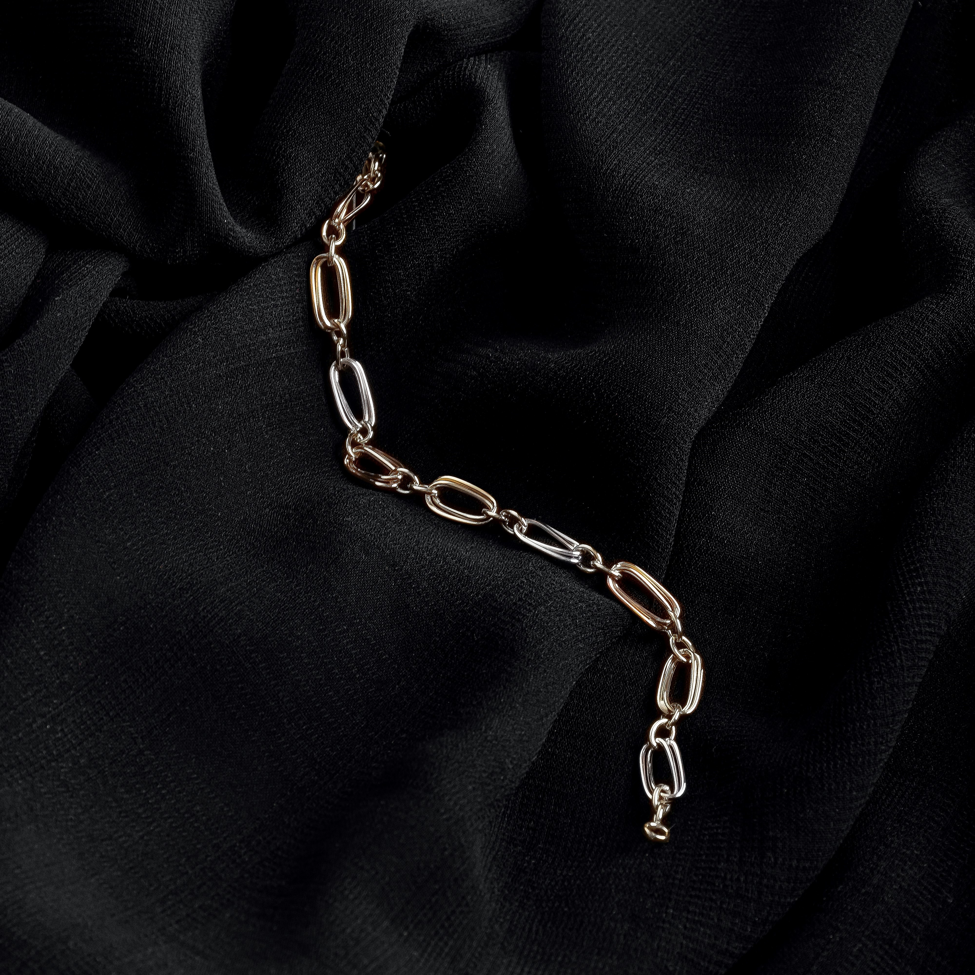 A golden necklace with 3 charms: a star with a pearl, a circle with diamonds and a moon