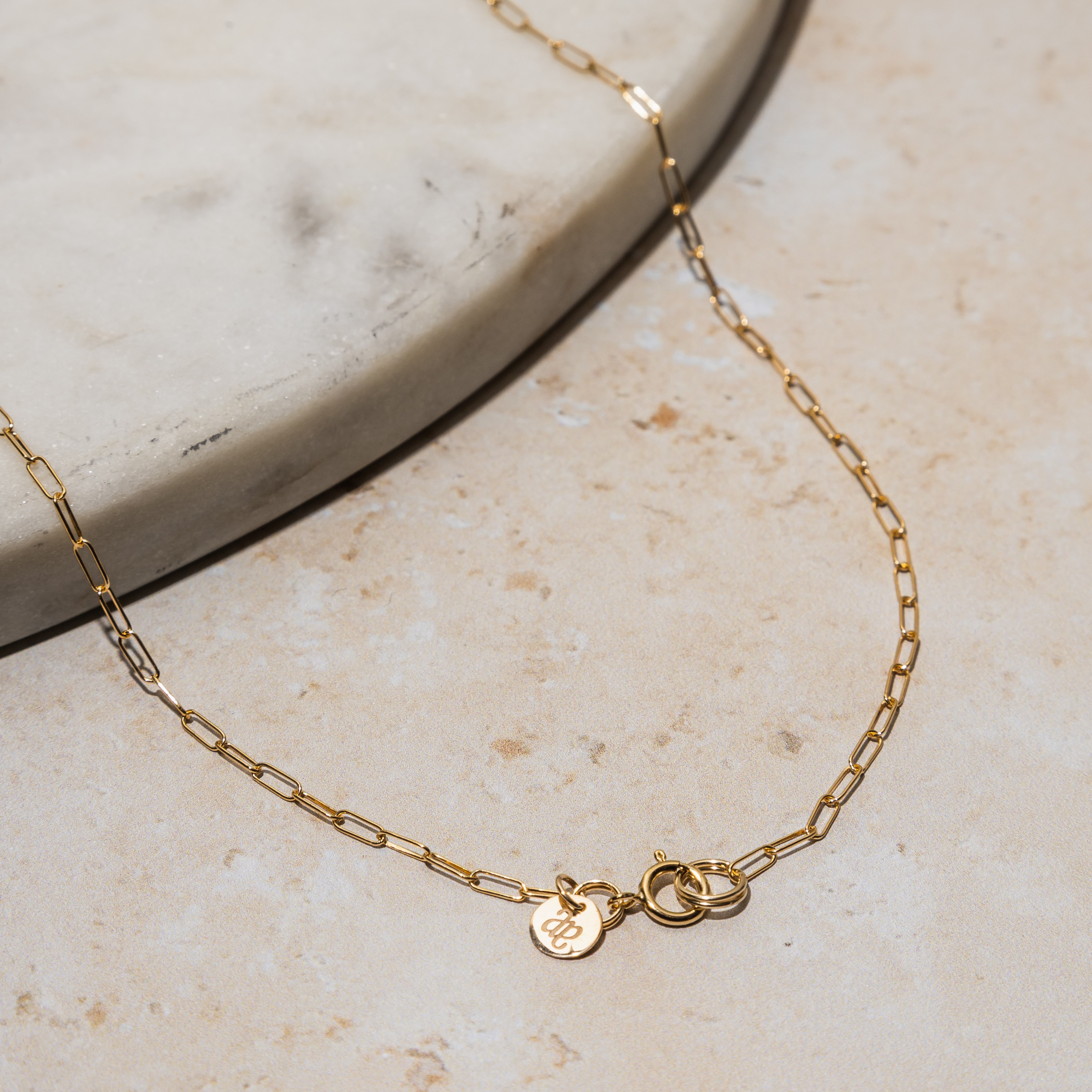 A minimalistic gold necklace with a delicate chain and one small, round charm