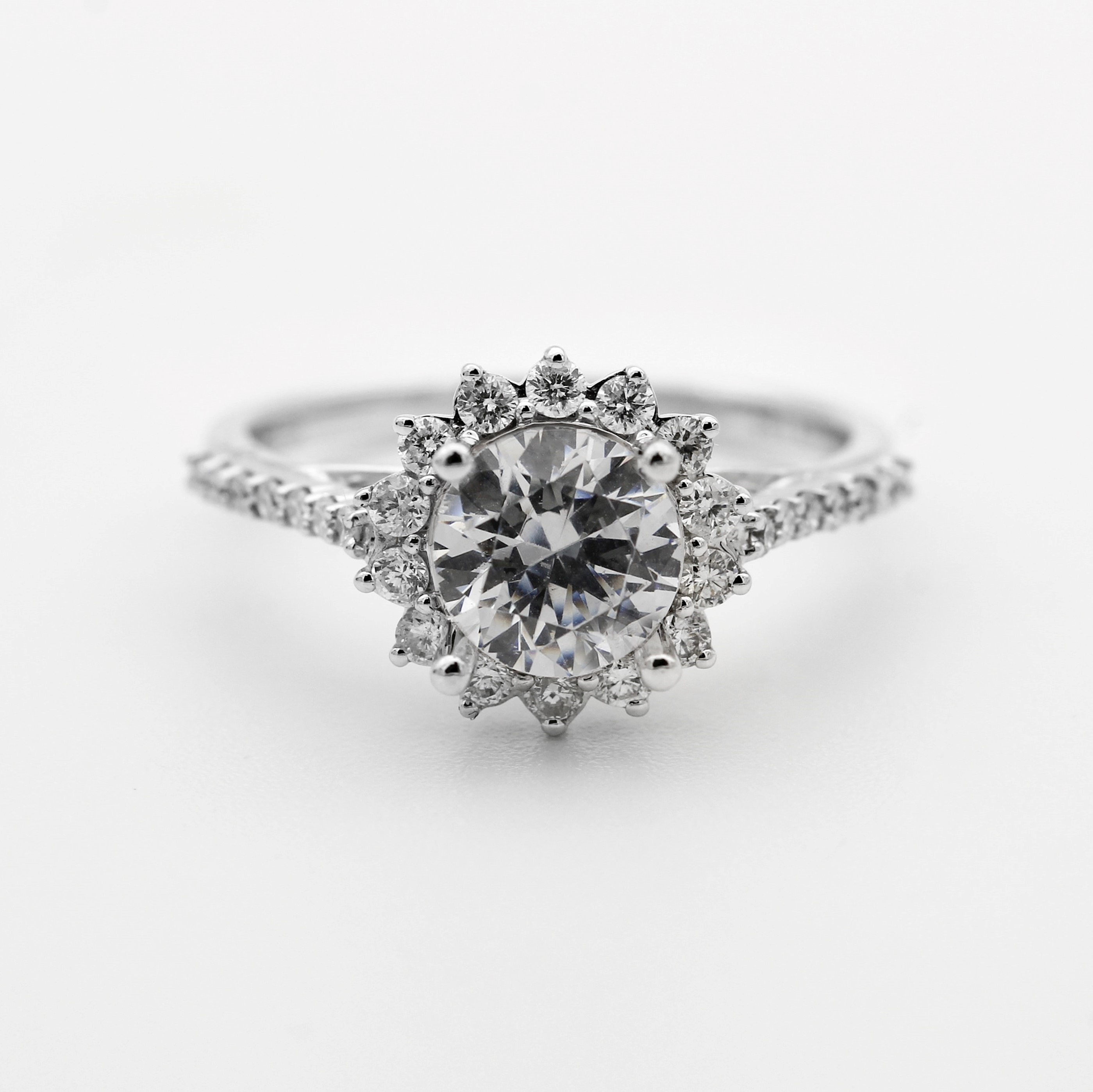 A silver ring with multiple small diamonds around and one big diamond surrounded by smaller diamonds