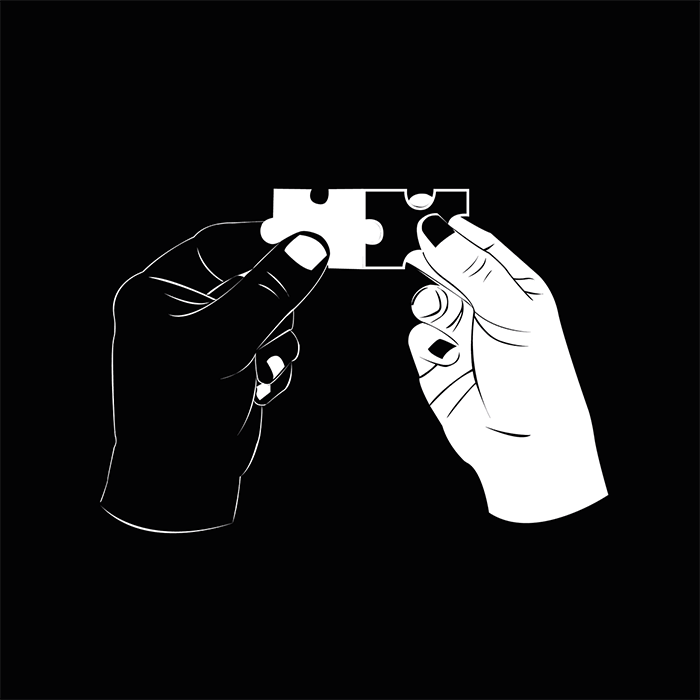 White and black hand holding puzzel pieces that fit tpgether