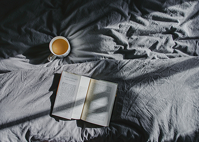 A picture of a book laying in a bed,
          with coffee